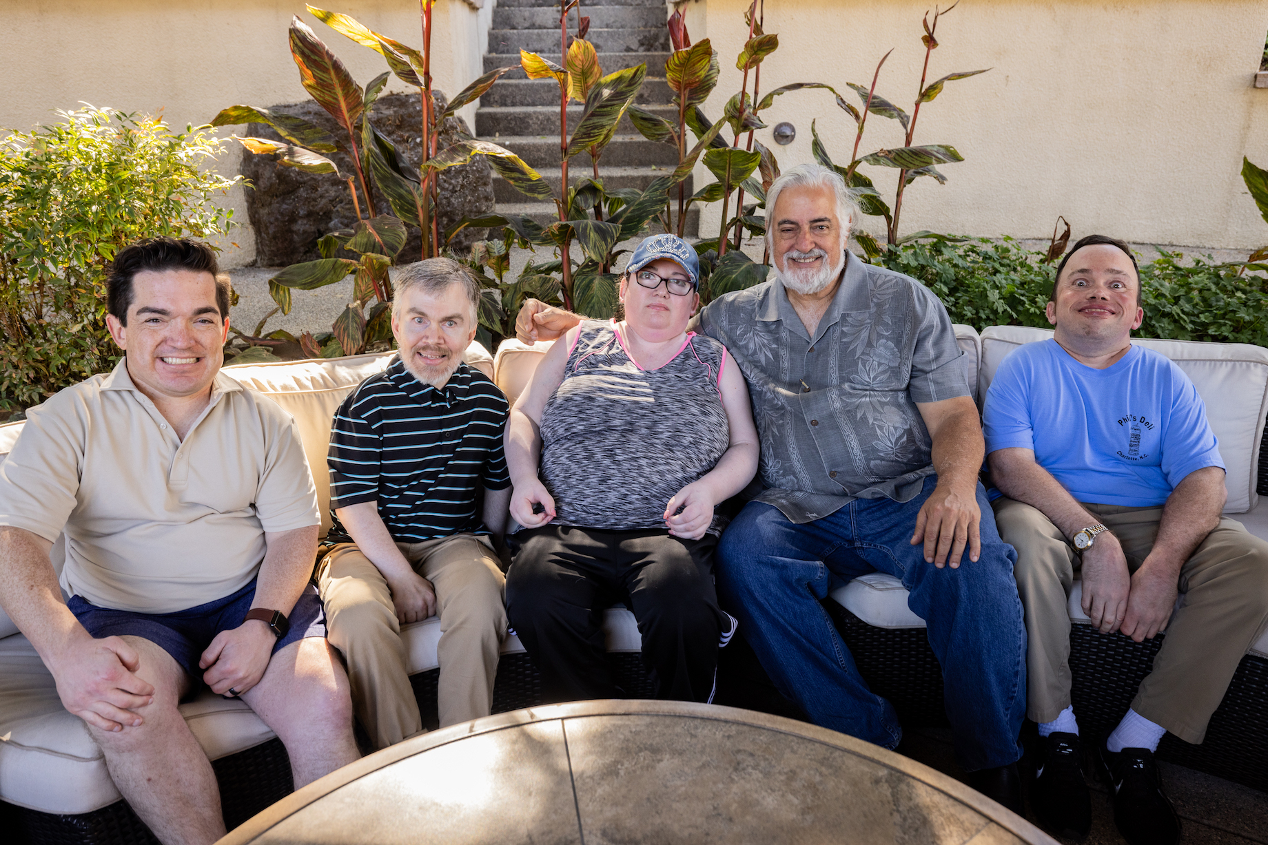 Five people sit together on an outdoor sofa