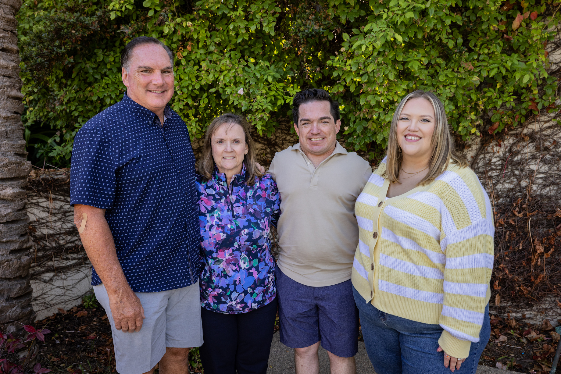 Four people stand in front of a garden background