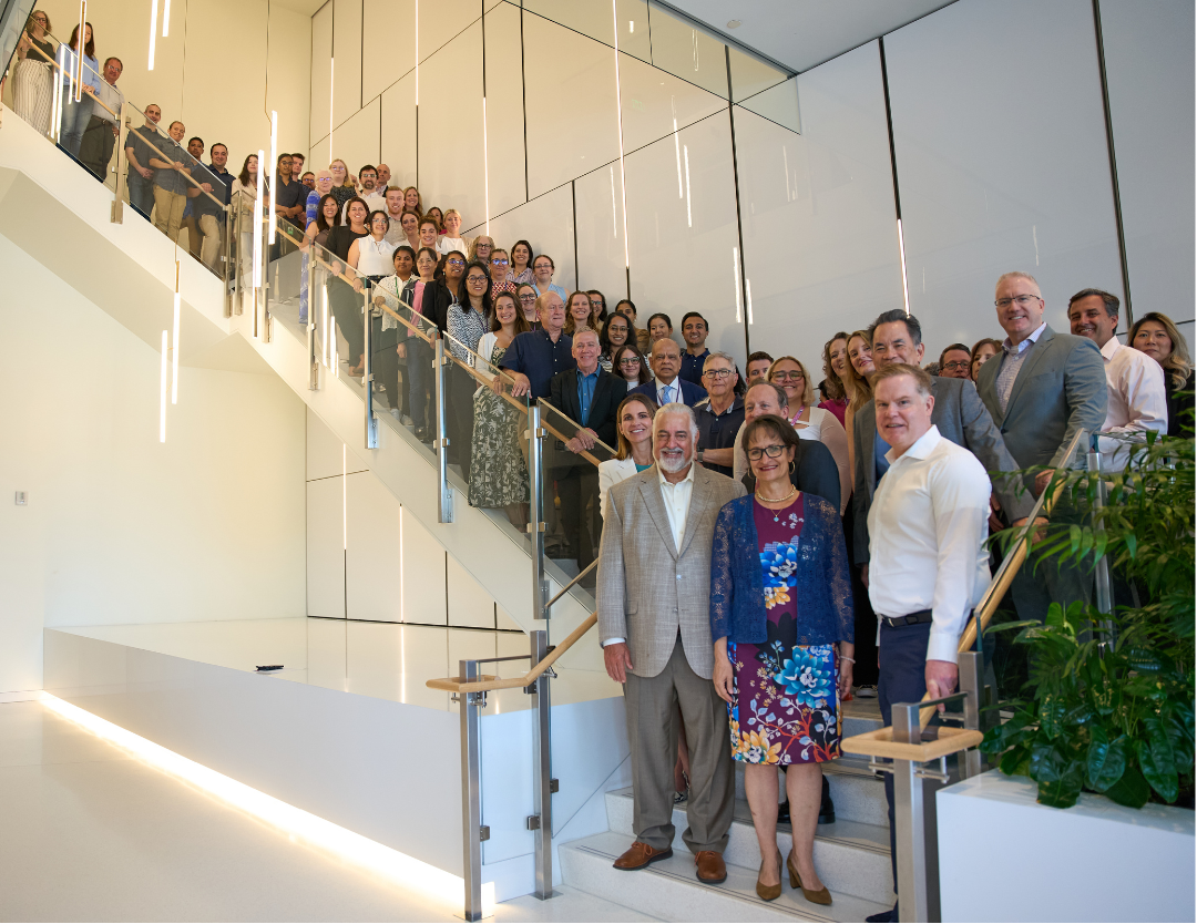 A large group of colleagues join together on a wide stairway for a team picture.